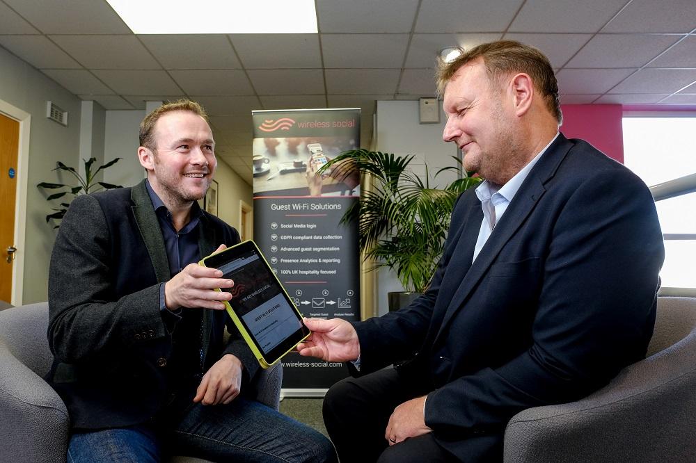 Two men sitting in an office using an Ipad