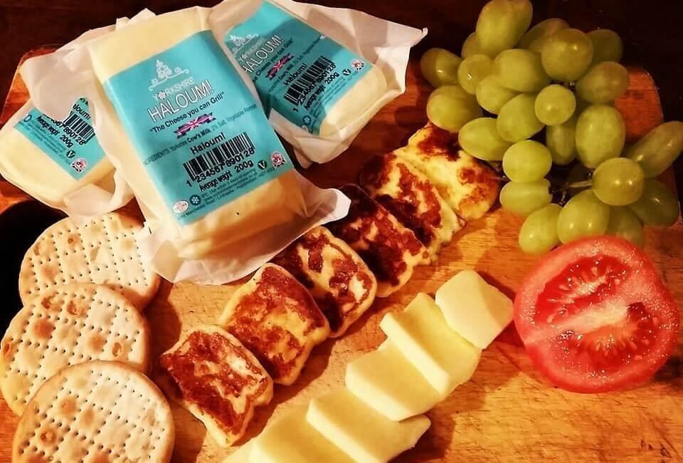 A cheeseboard with a selection of cheese, crackers, tomatoes and grapes