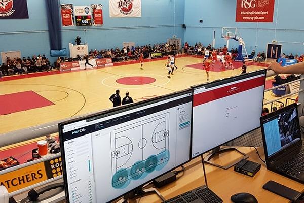 Zeetta Networks software on computer monitors with a n indoor basketball court in the background