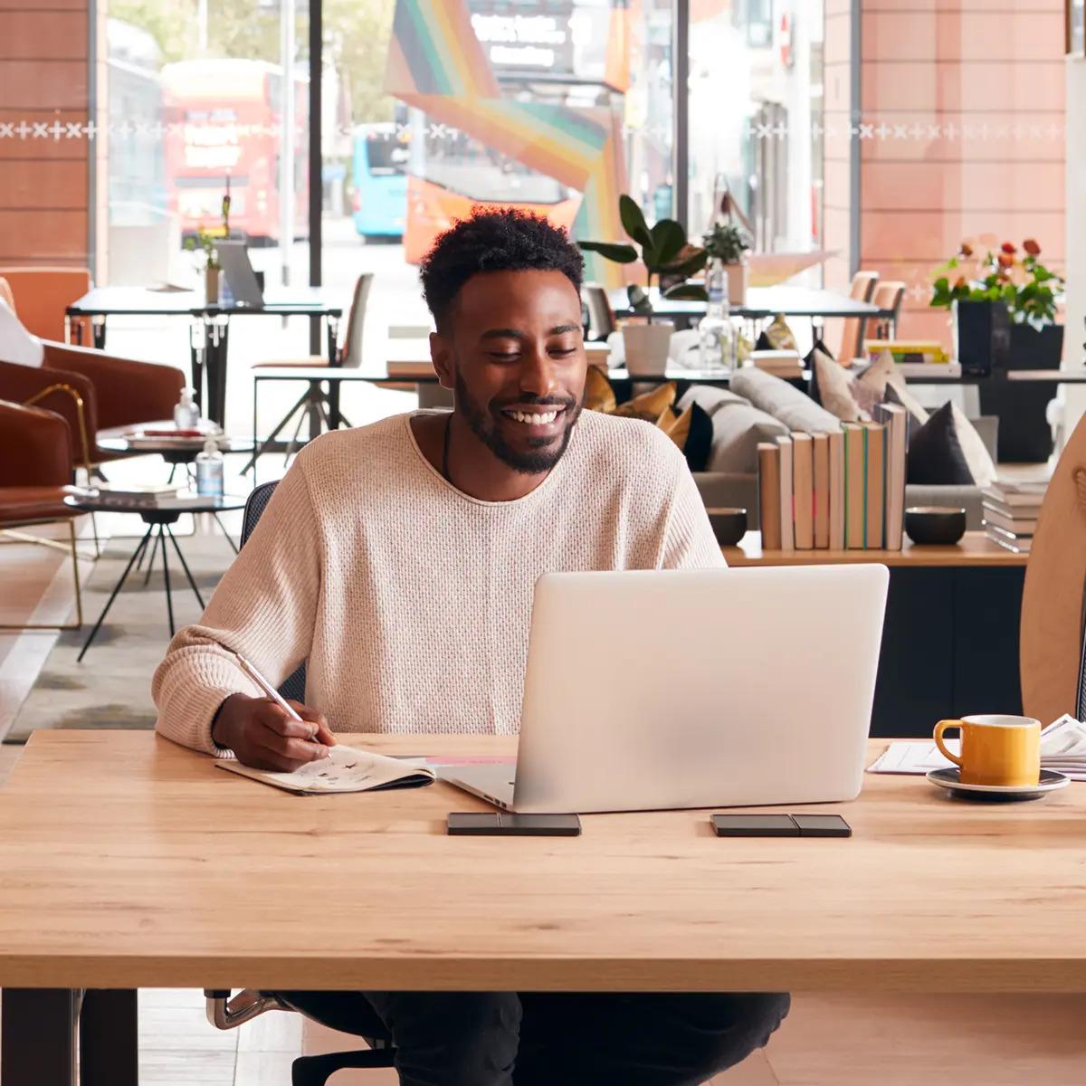 Staff sat in office looking at laptop smiling, wearing casual clothing