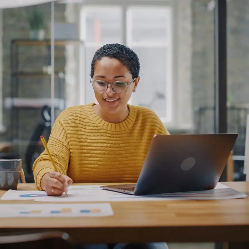 Female staff member sitting at a table looking at a laptop