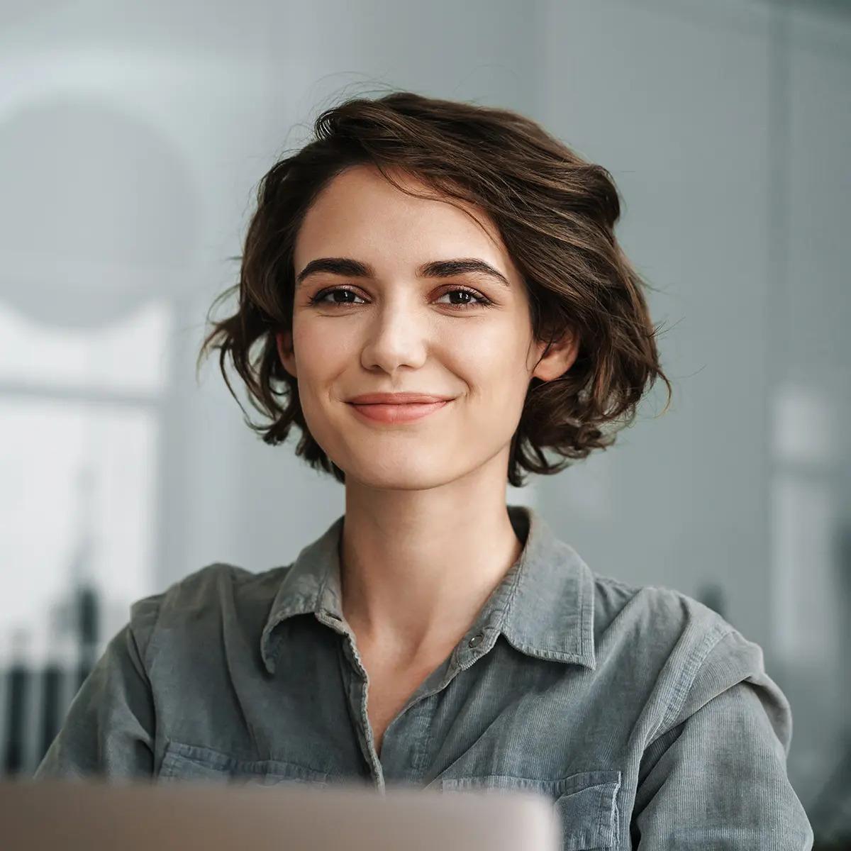 Female colleague in boardroom wearing a grey shirt smiling at the camera