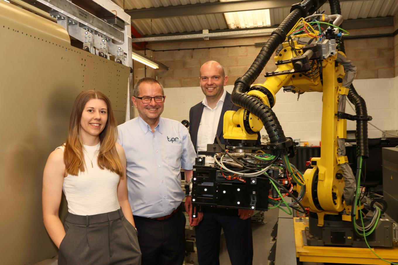 two men and one lady standing next to a robotic system 