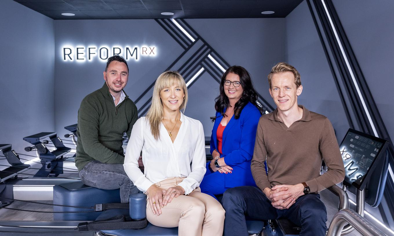 Photo of Reform RX founders Yvette and Neil McGaffin with Mark Sterritt from British Business Bank and Claudine Owens from Clarendon Fund Managers in a gym room with reformer pilates equipment