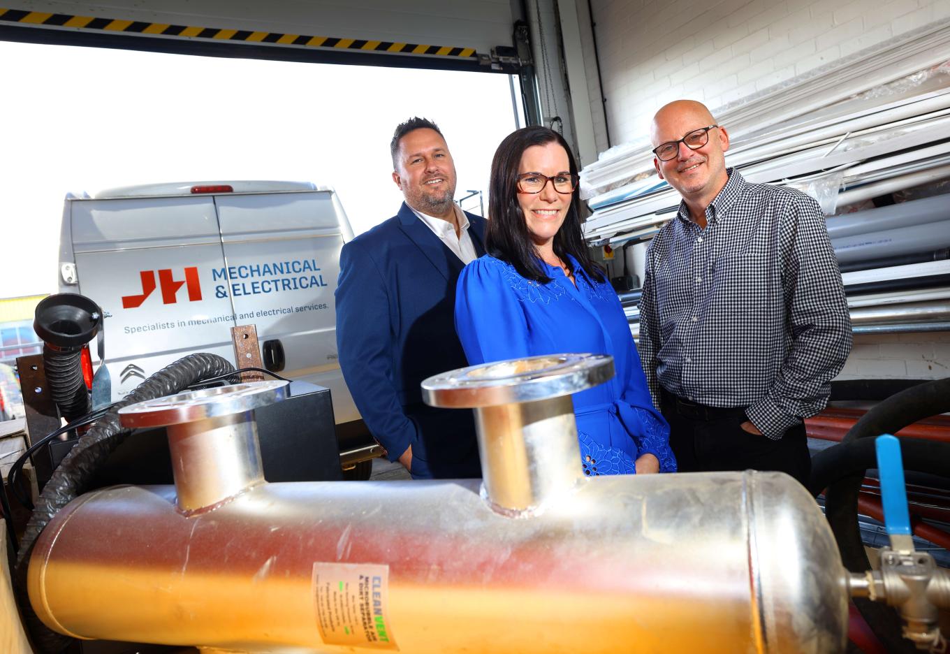 Three individuals positioned beside a large industrial machine