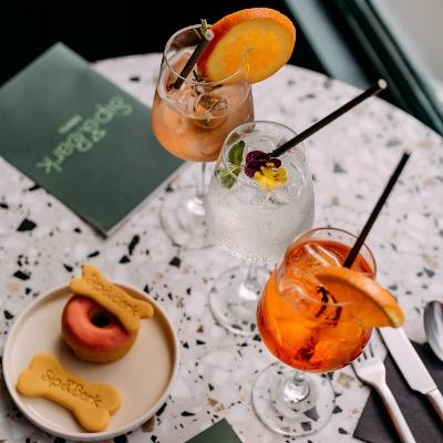 Photo of a cafe table with cocktails and a plate with dog biscuits