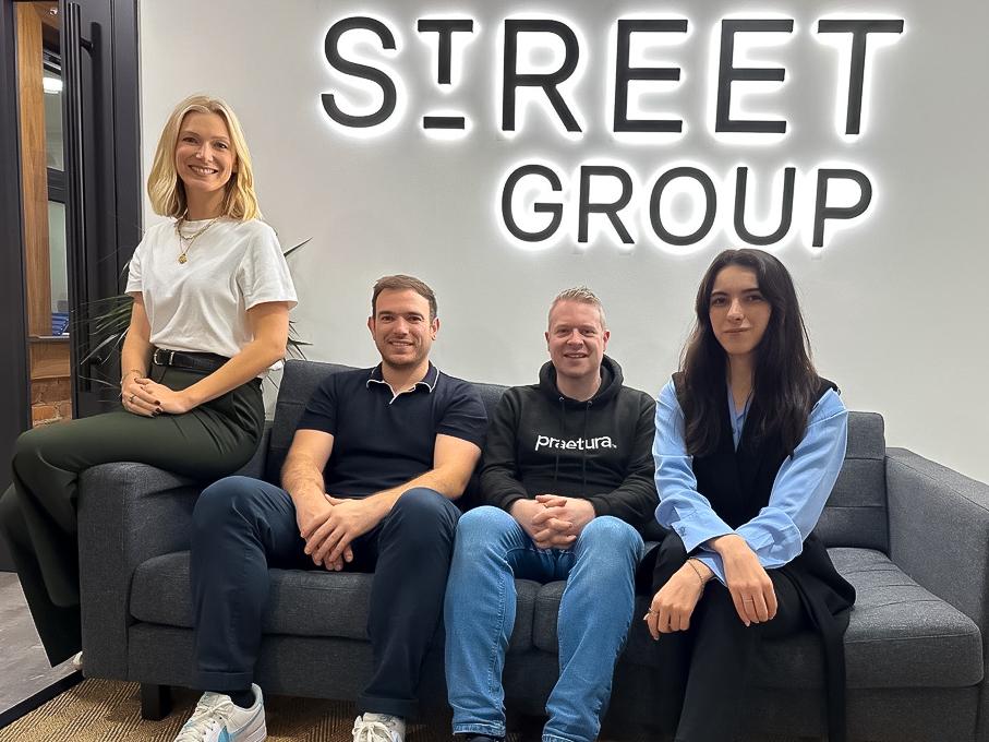 a group of people sitting on a couch behind street group logo