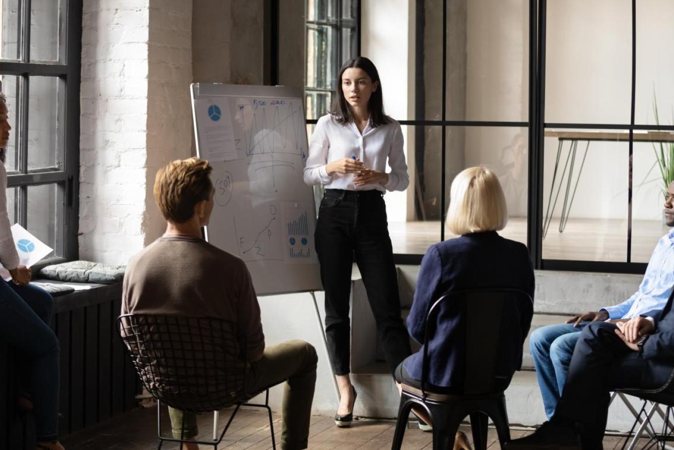 woman standing giving a presentation to colleagues in an office