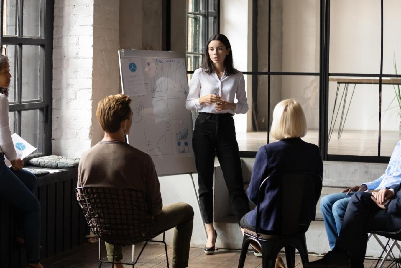 woman standing giving a presentation to colleagues in an office