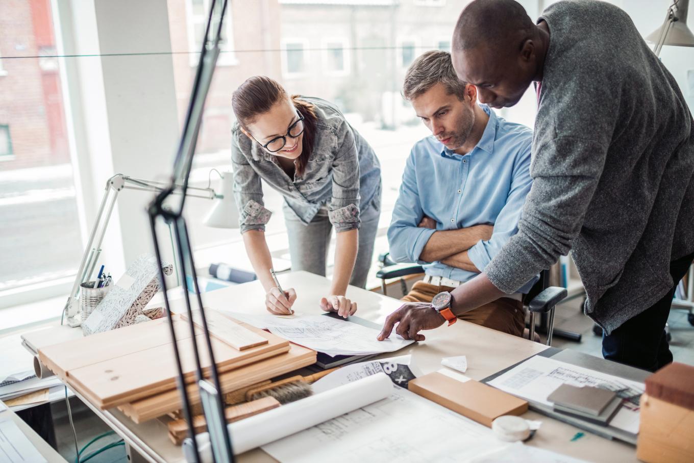Three men looking at technical drawings of some kind