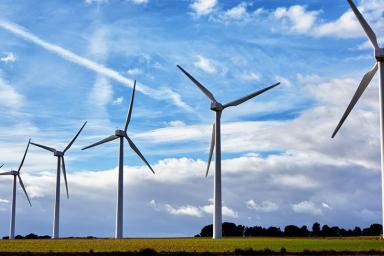 a row of windmills in a field with a sky full of clouds